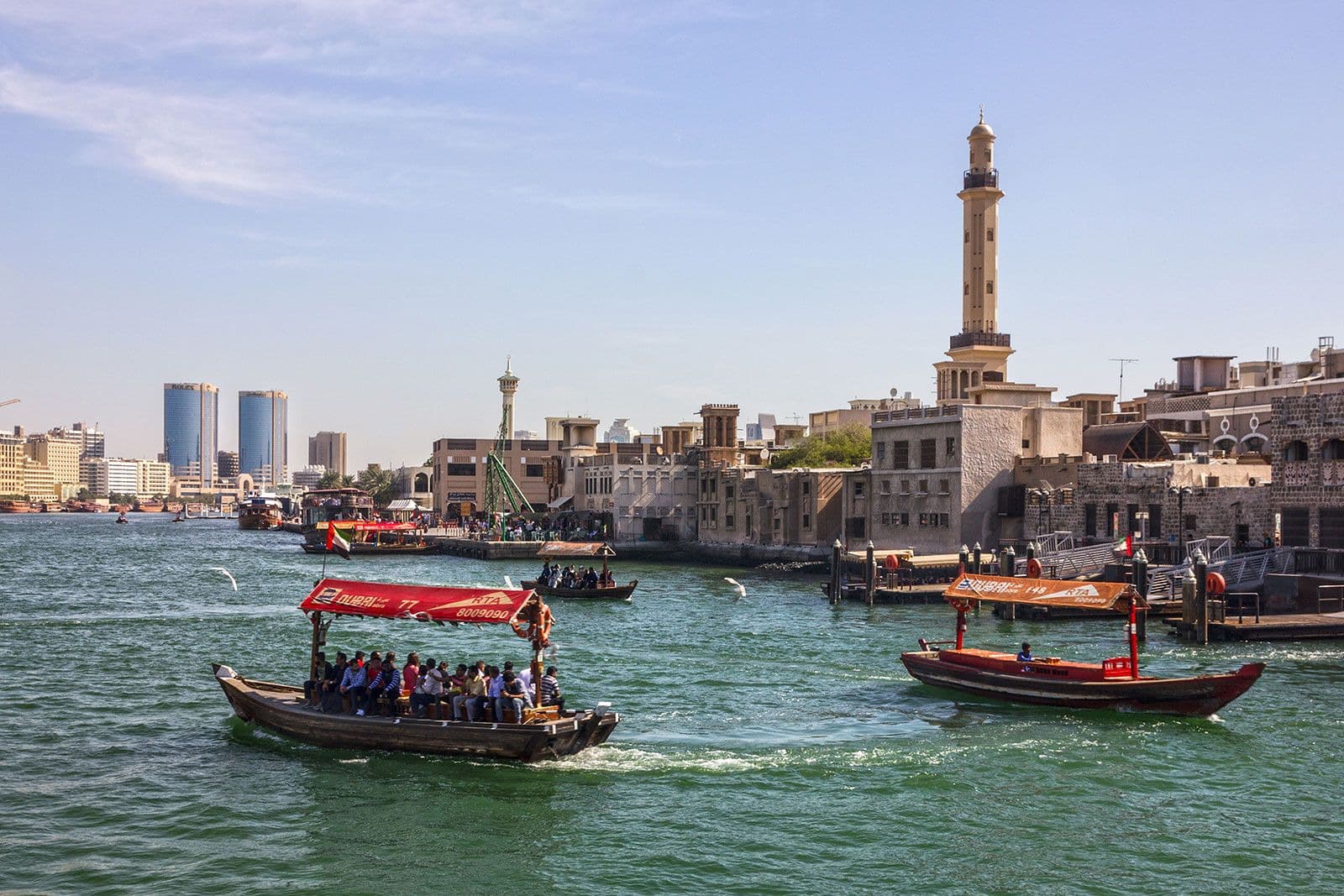An abra crossing Dubai Creek with the old town behind it