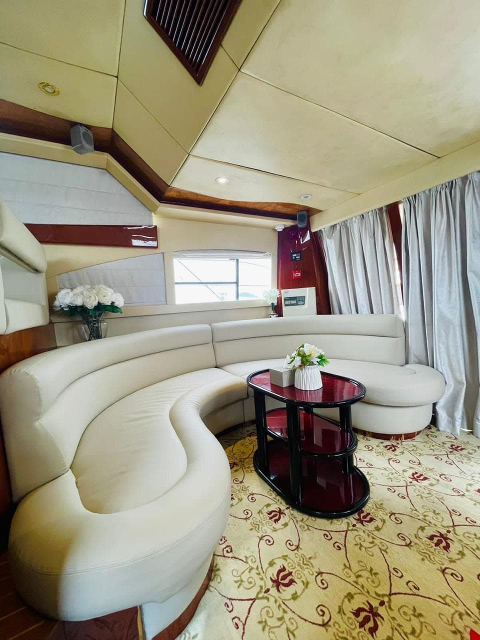 The saloon inside the yacht: a curved cream leather sofa around a lacquered table
