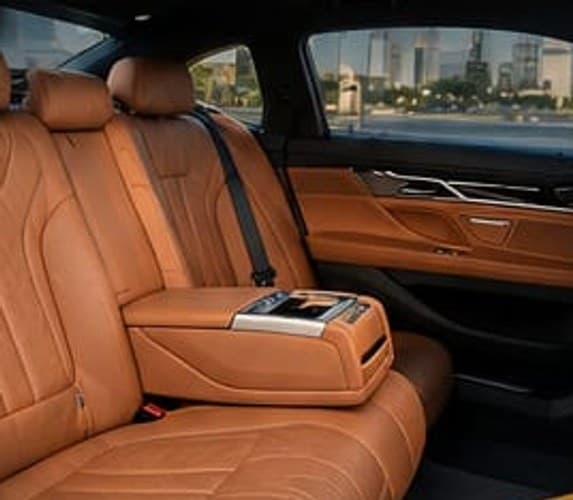 The 7 Series rear bench in tan leather, armrest down, the city through the side window
