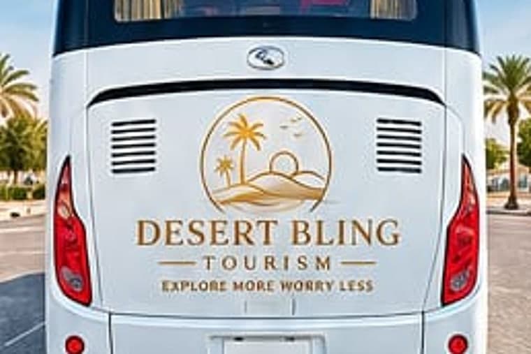 The back of the coach in white livery, the Desert Bling Tourism mark across it between the tail lights