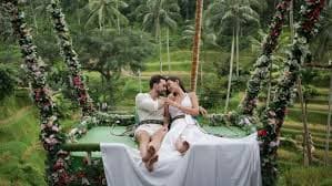 A couple on a flower-draped swing bed above the Ubud rice terraces