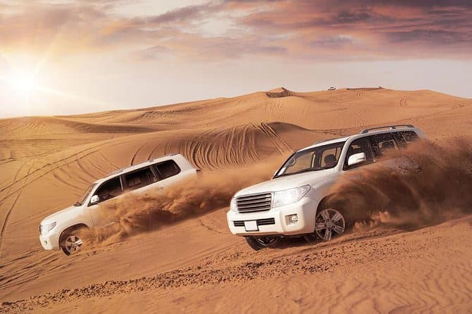 Two 4x4s dune bashing across the desert on a Dubai safari