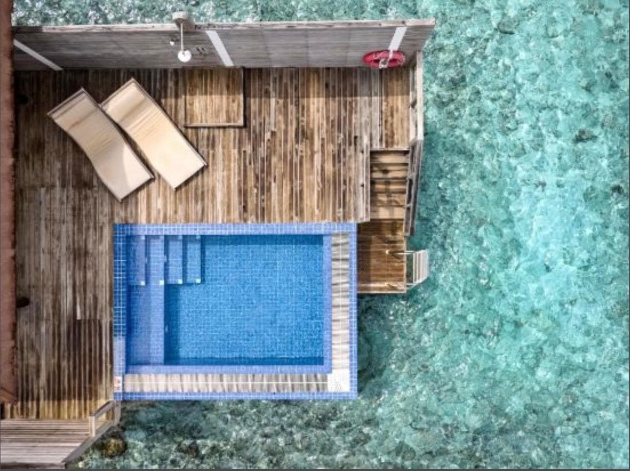 The villa's deck from directly above: plunge pool, loungers and steps down into the lagoon