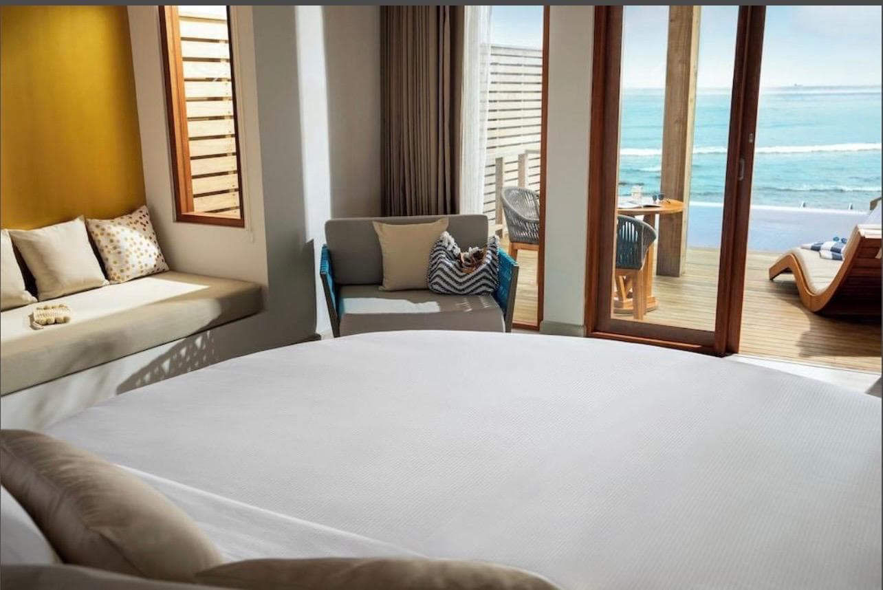 Inside the water villa, the bed facing folding doors that open onto the ocean