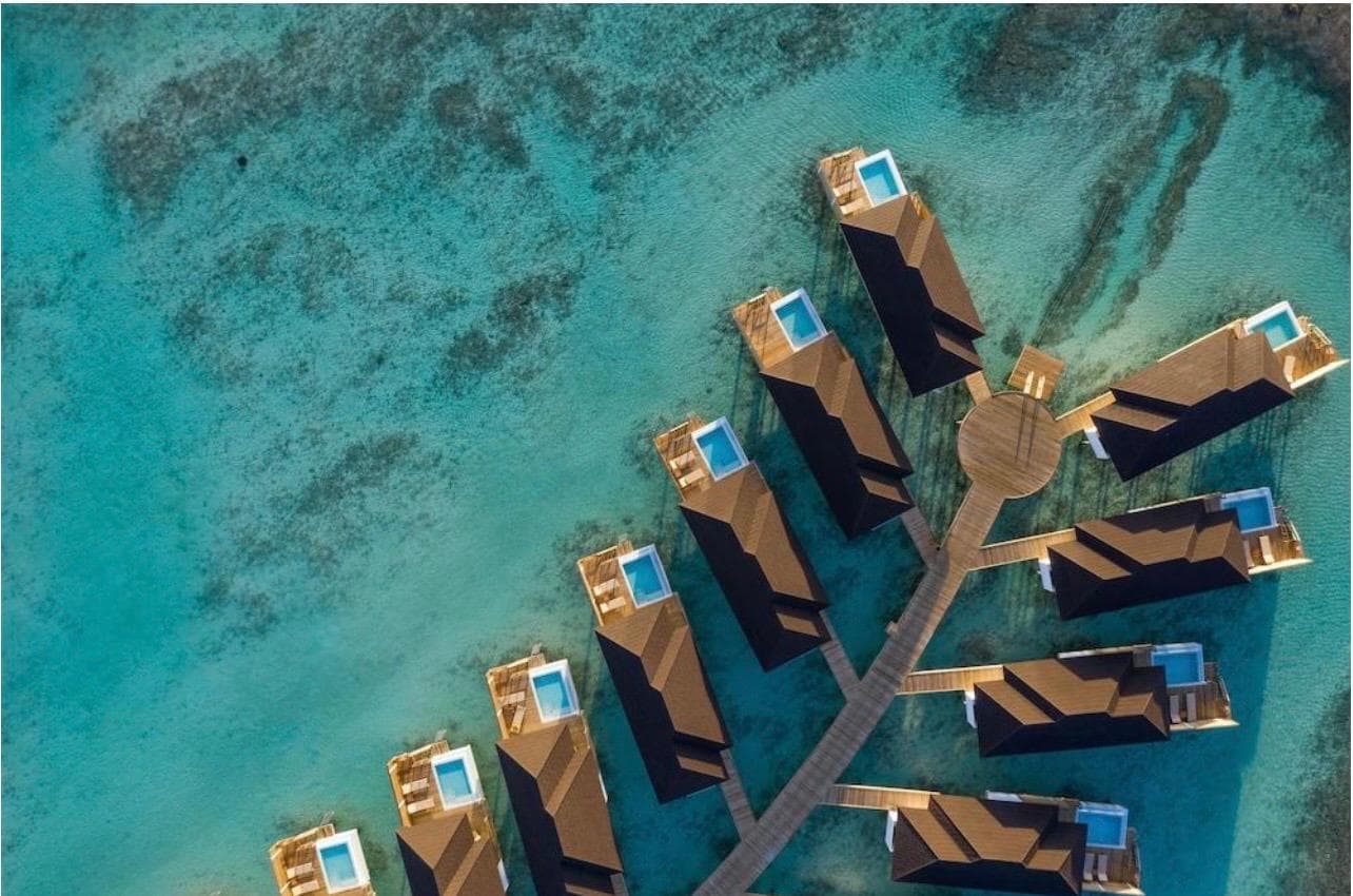 The resort's overwater villas from the air, each with its own plunge pool over the reef